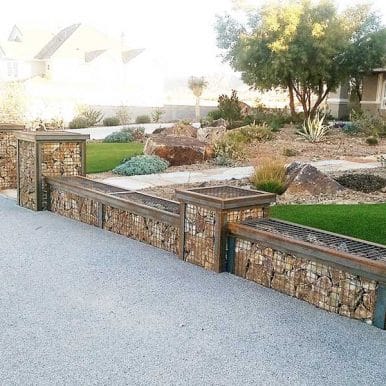 A modern residential driveway landscape featuring stone filled retaining walls to help when choosing between welded and woven gabion baskets.